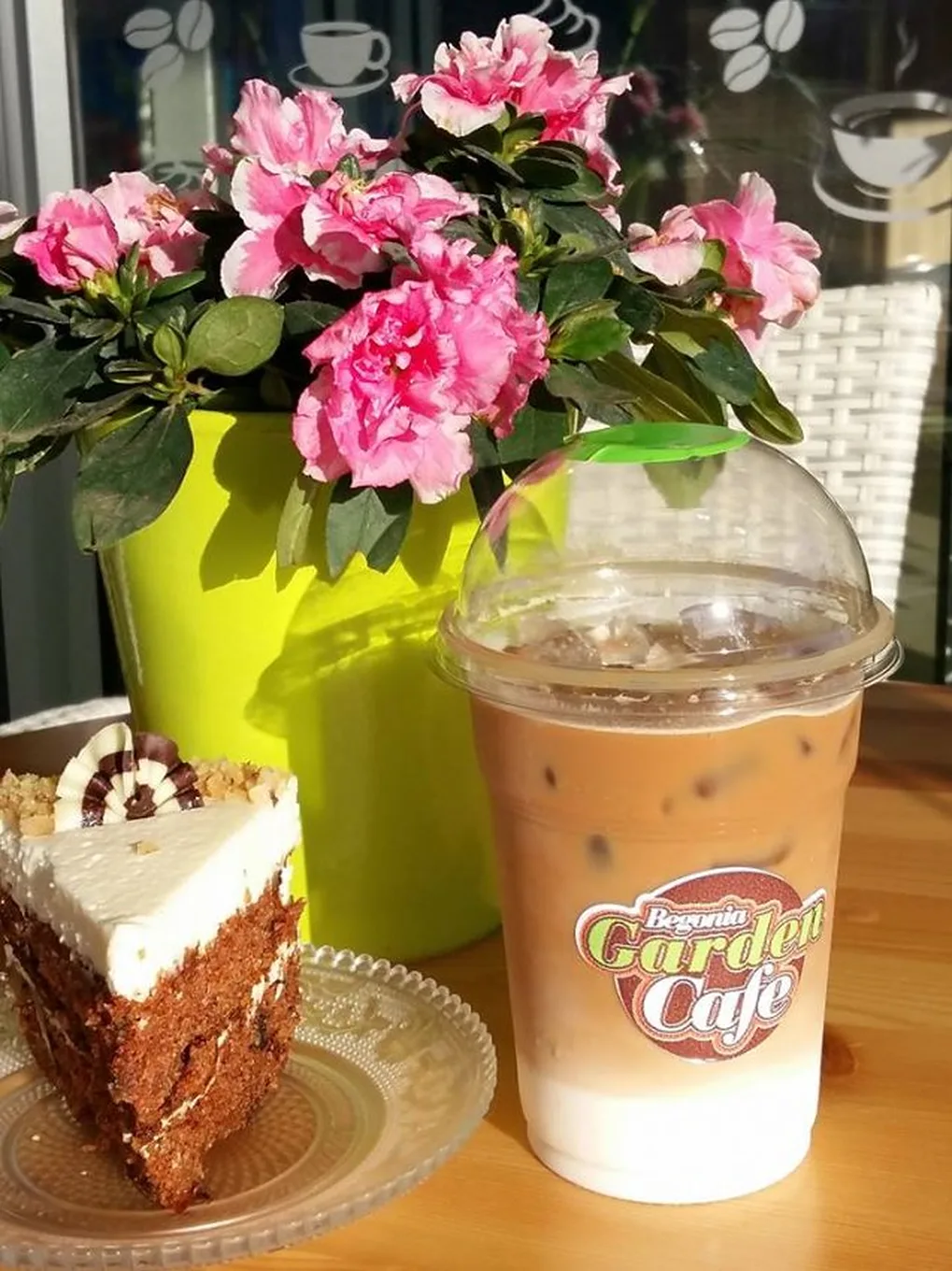 Carrot cake and iced coffee next to a pink azalea