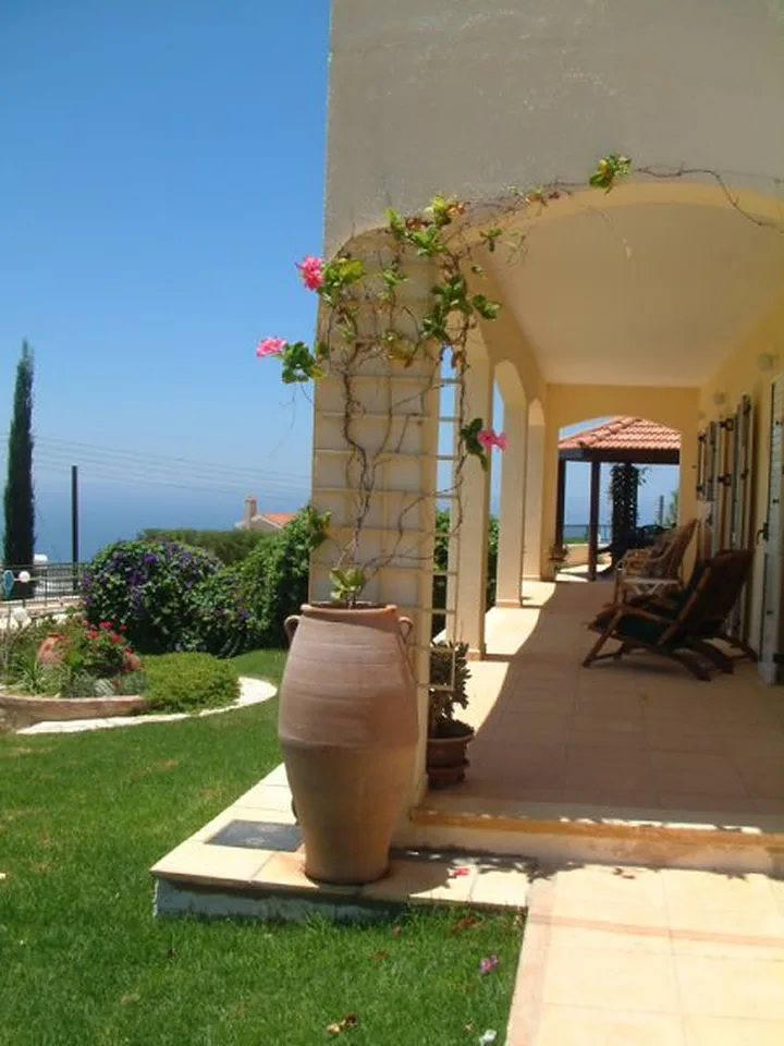 Terrace with a tall clay pot and climbing flowers above the sea